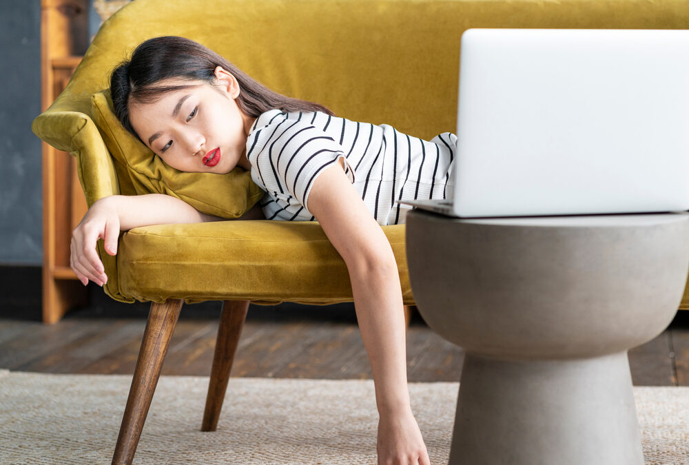 Woman lying face down on couch looking at her computer