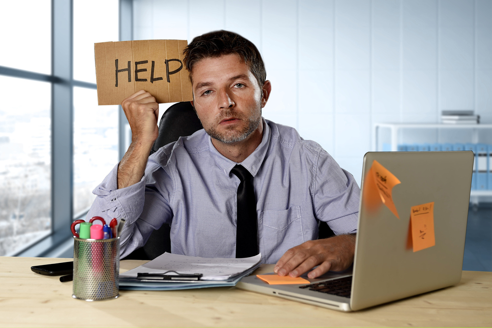 Person at computer holding up a help sign