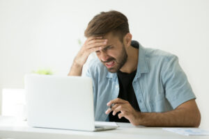Man looking confused while reading on his laptop