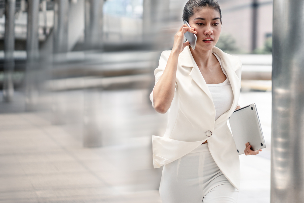 Woman talking on phone and running to a meeting