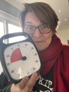 Liane holding up an analog timer called a Time Timer that she uses when she starts to feel overwhelmed. 